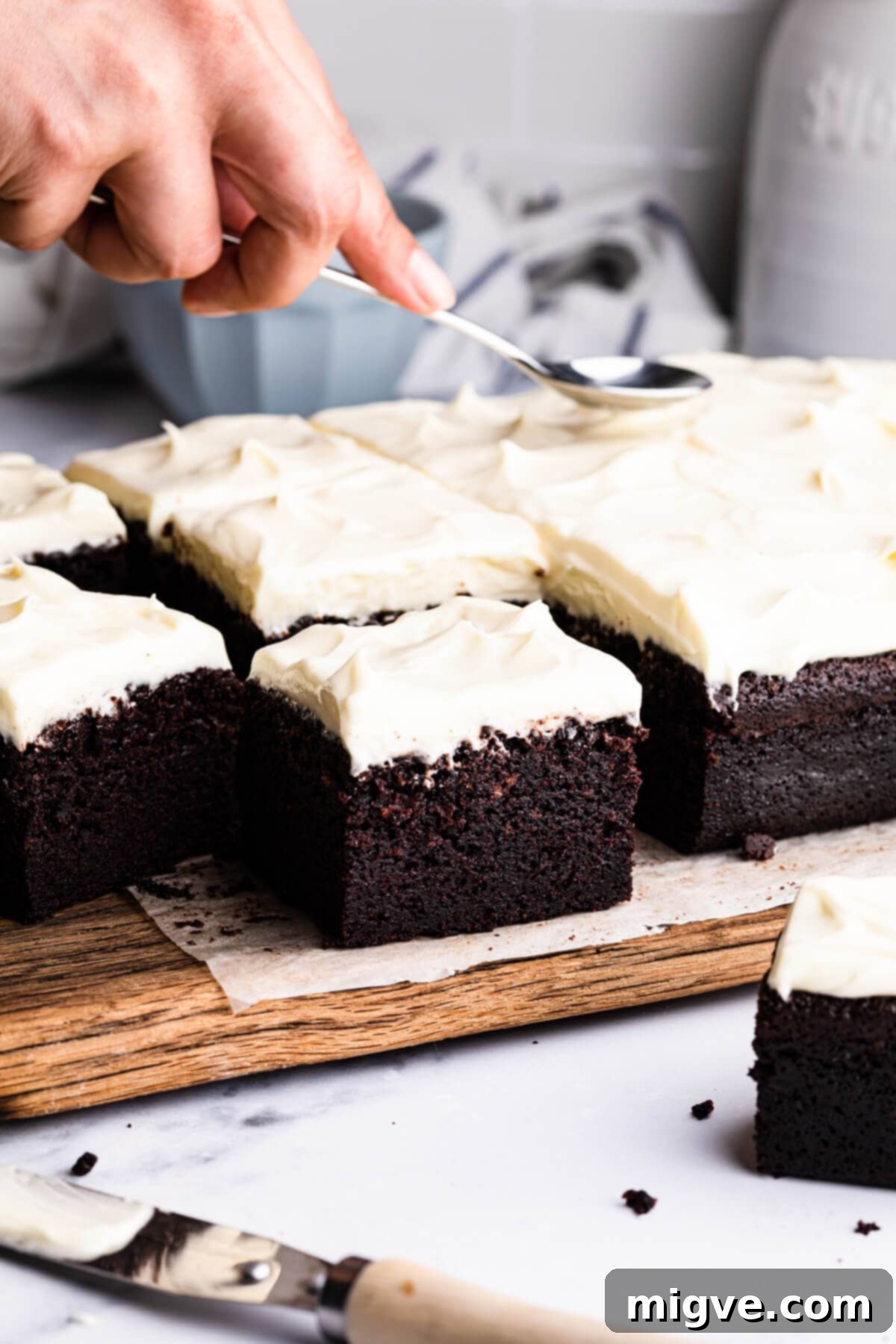 Guinness chocolate traybake cake with cream cheese frosting on a wooden chopping board.