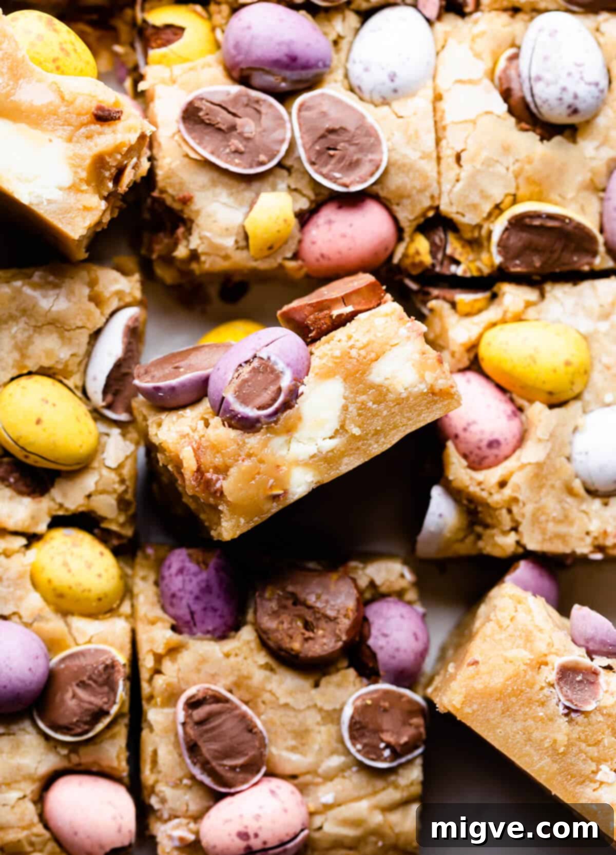 Speckled Spring Blondies 11 Top-down close-up photo of freshly baked mini egg blondies, already cut into squares, showcasing their colorful topping.