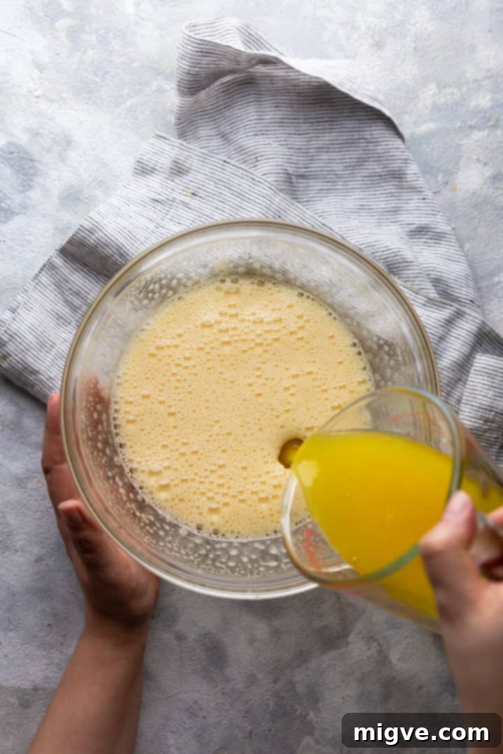 top view of melted butter being poured into whipped eggs