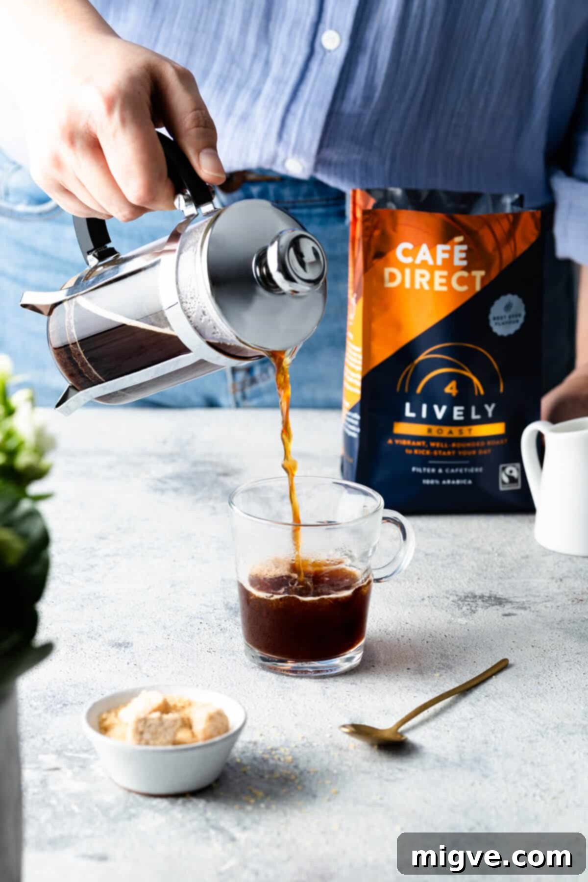 Rich, freshly brewed coffee being gracefully poured into a transparent glass cup, showcasing its inviting color and texture.