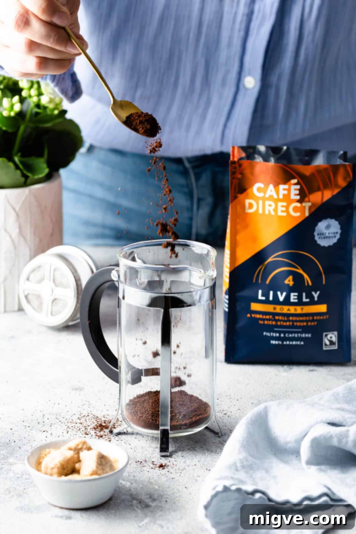 A perfectly portioned spoonful of coffee grounds being added to a cafetiere, a key step in crafting the ideal brew.