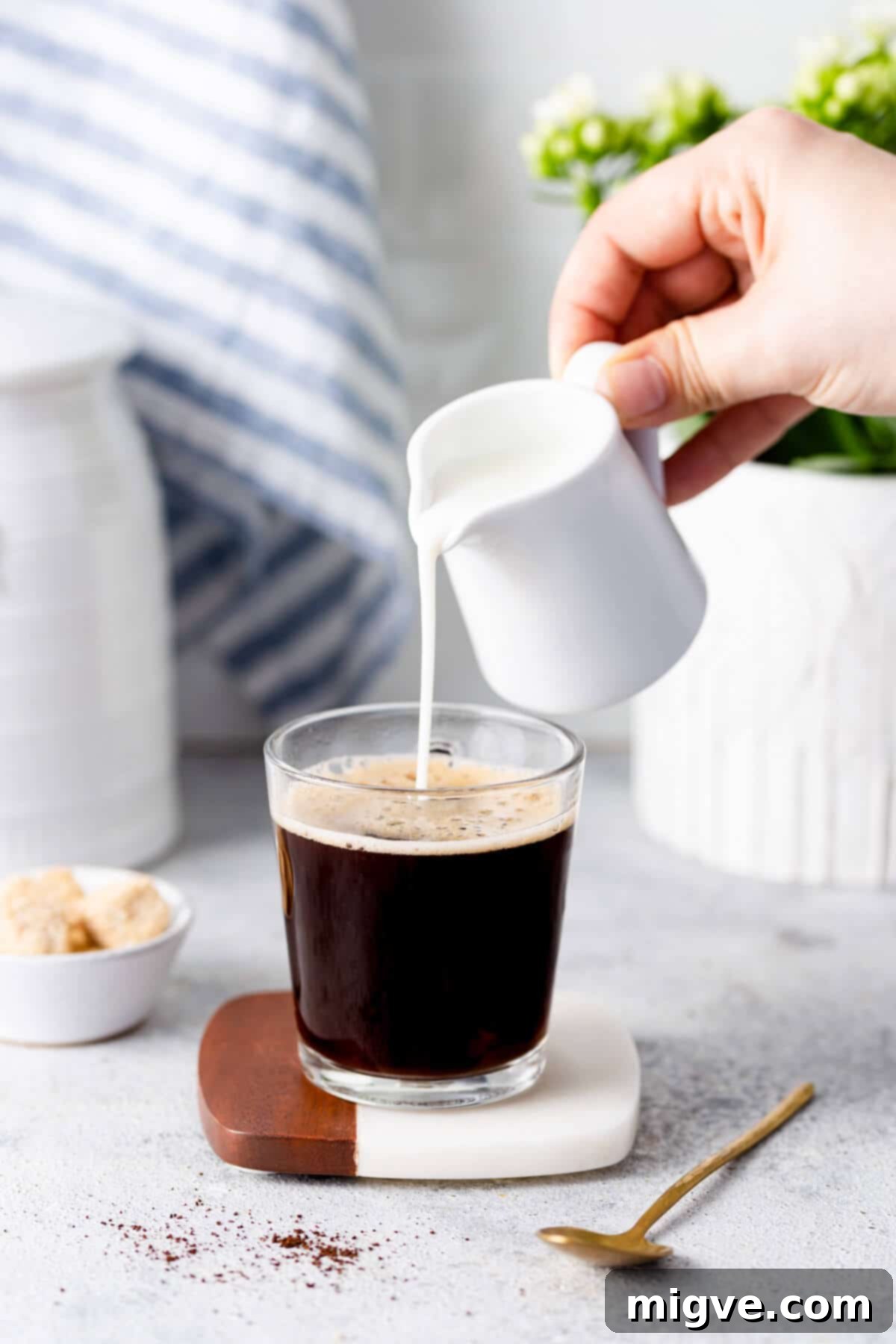 A delicate stream of fresh milk being poured into a warm cup of coffee, creating a beautiful swirl of creamy richness.