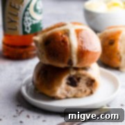 Two chocolate chip hot cross buns stacked on top of each other, showcasing their fluffy texture and melted chocolate.