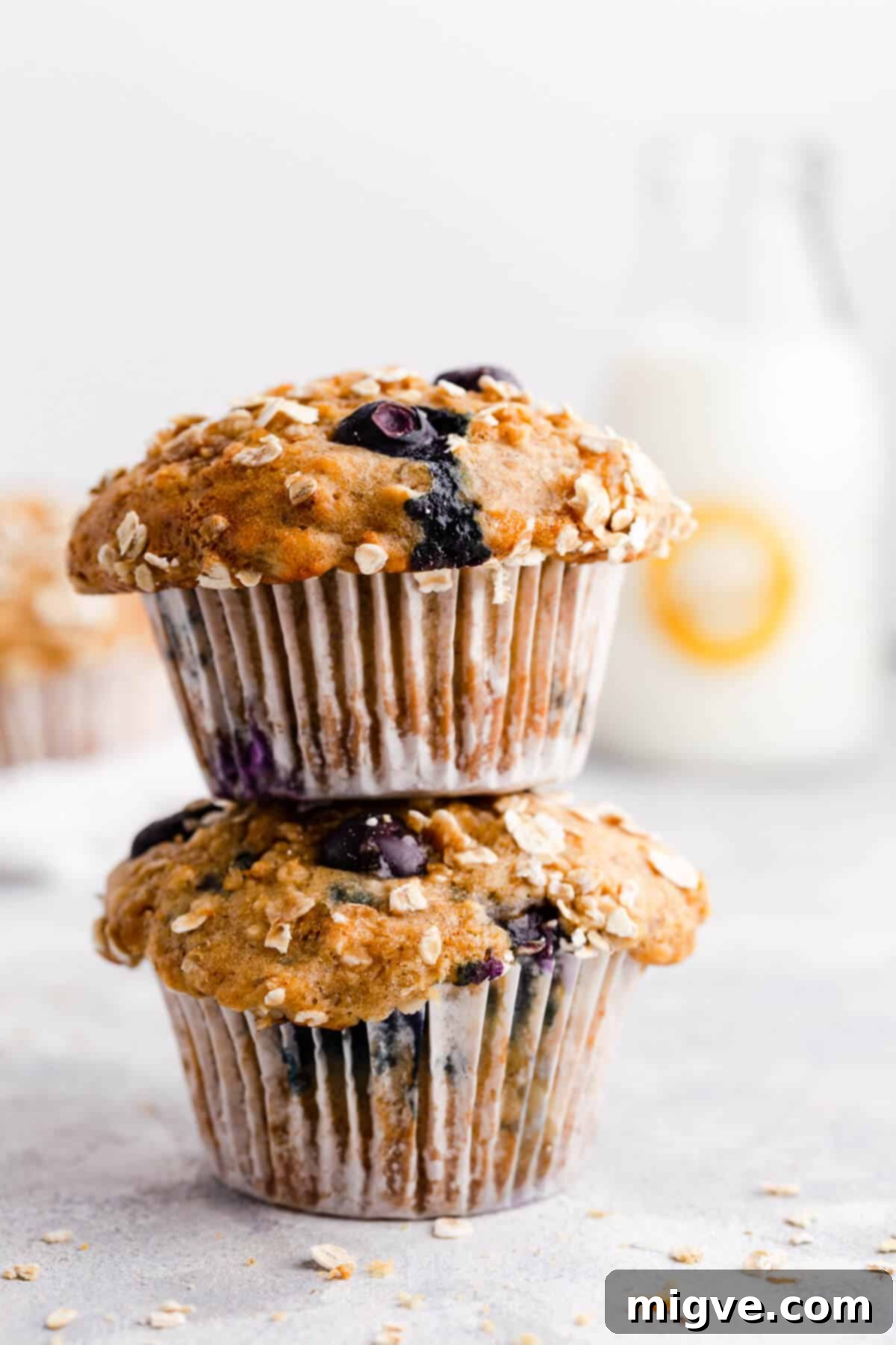 Two perfectly baked banana and blueberry muffins, stacked on a rustic surface, showcasing their golden-brown tops and moist interior. Ideal for breakfast or a sweet snack.