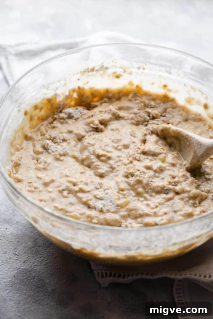 Close-up side view of a mixing bowl containing freshly prepared banana and blueberry muffin batter, showing its lumpy texture.