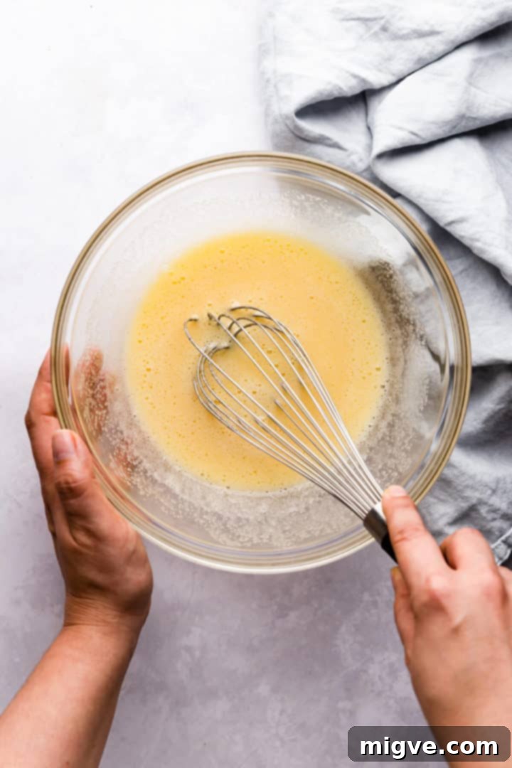 overhead view of a person whisking eggs and sugar in a bowl