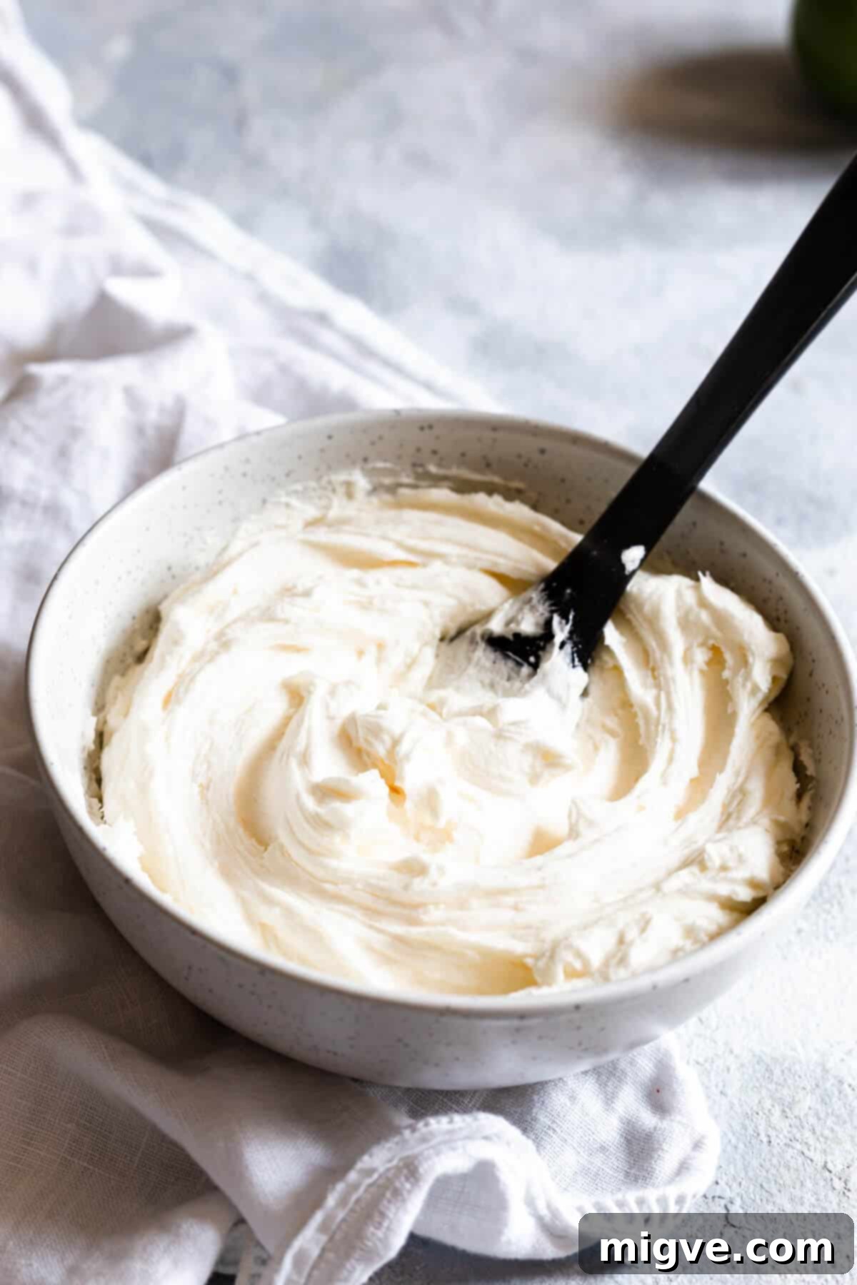 Side view of a bowl brimming with creamy, smooth butter icing, ready for piping onto cupcakes.