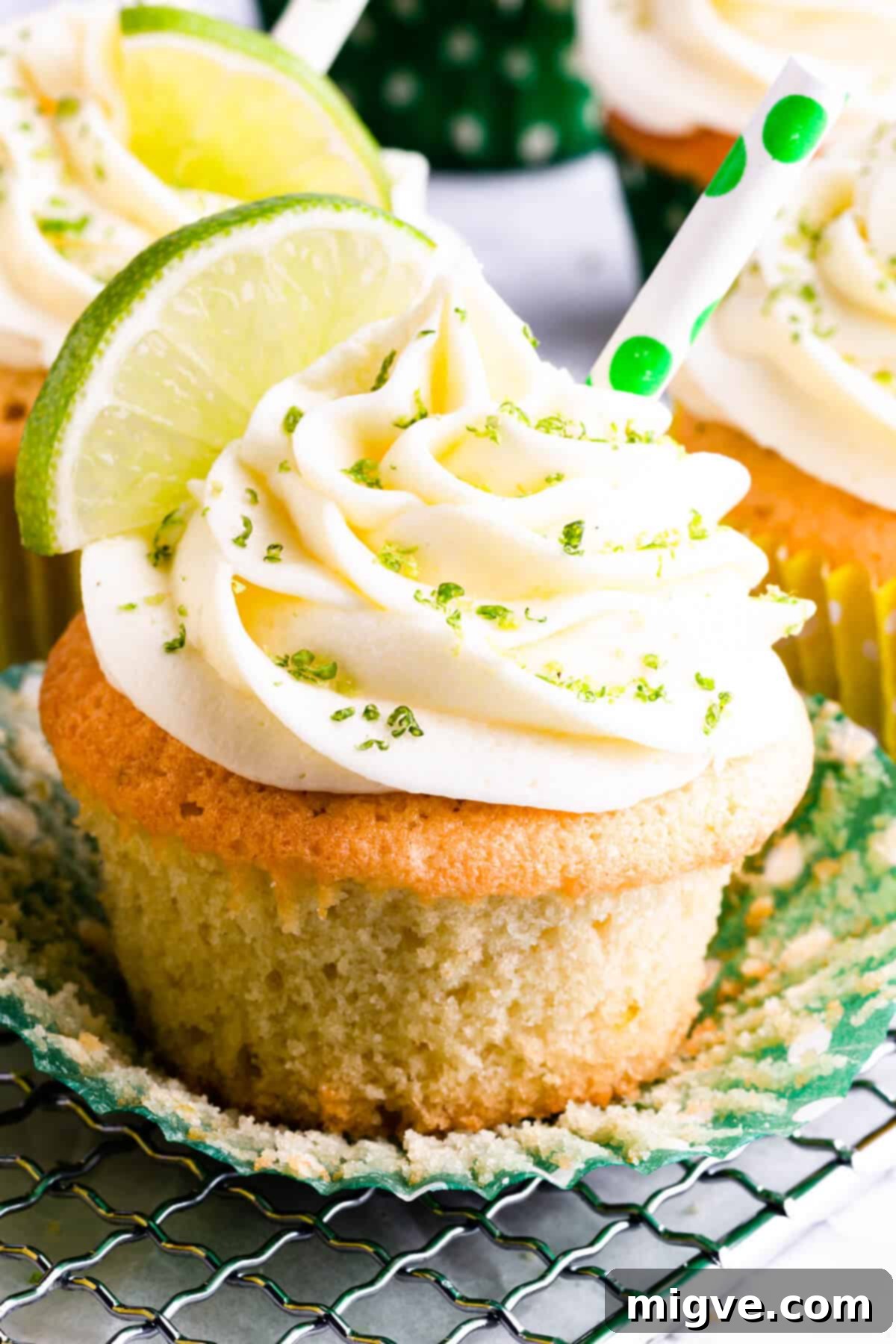 Super close-up of a beautifully frosted Gin and Tonic Cupcake, adorned with vibrant lime zest, ready to be enjoyed.