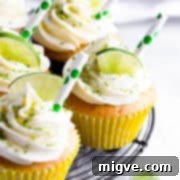 Side close-up of a perfectly decorated Gin and Tonic Cupcake, garnished with a slice of fresh lime.