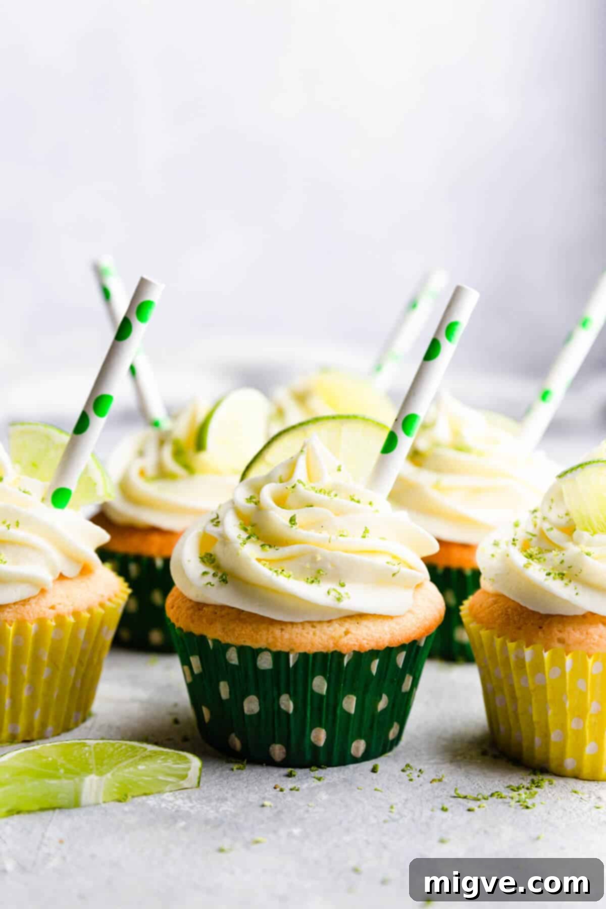 Straight-ahead view of decorated Gin and Tonic Cupcakes, adorned with small paper straws, ready to be served.