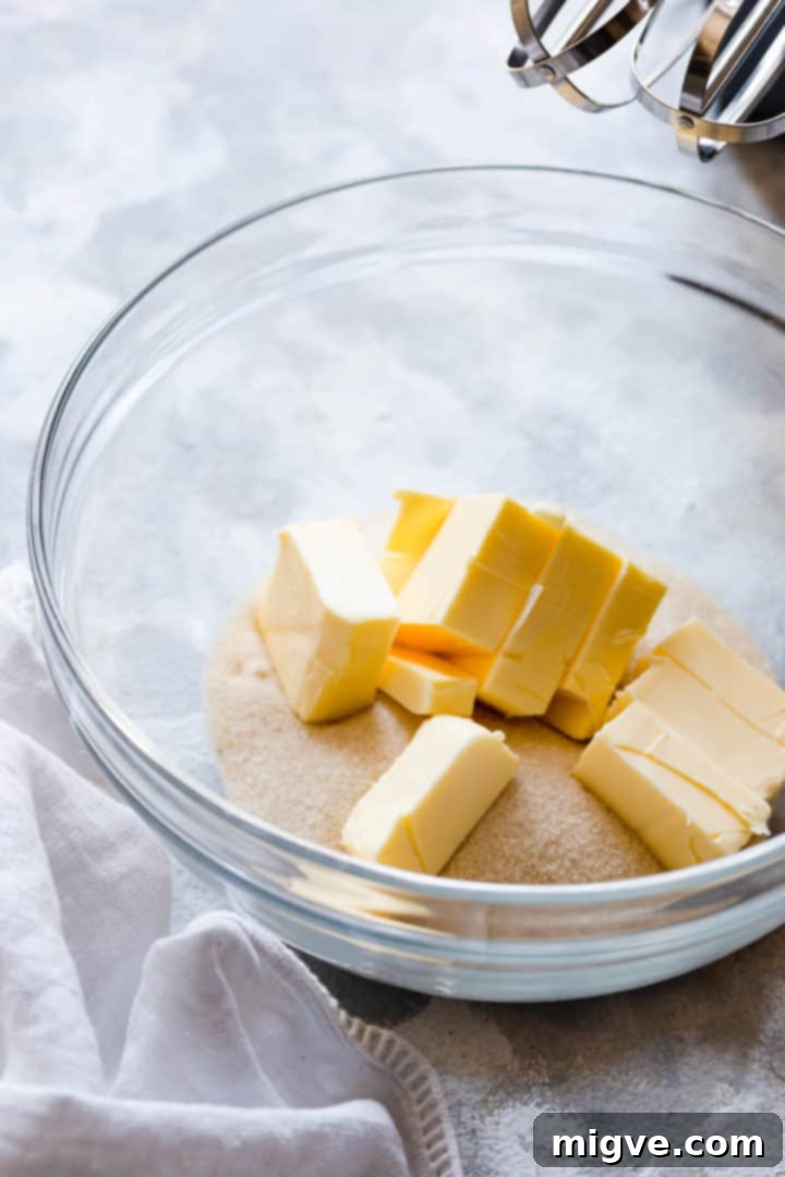 Side close-up of a glass bowl containing butter and sugar, just starting the creaming process.