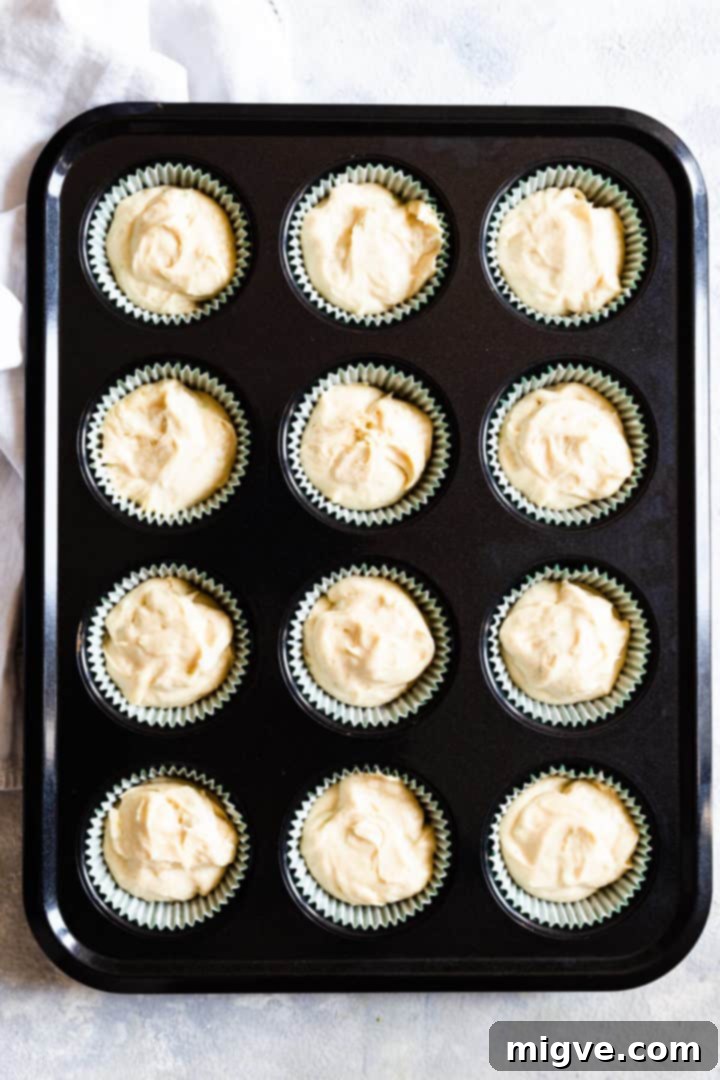 Top view of a 12-hole cupcake tin neatly filled with cake batter, ready to go into the oven.