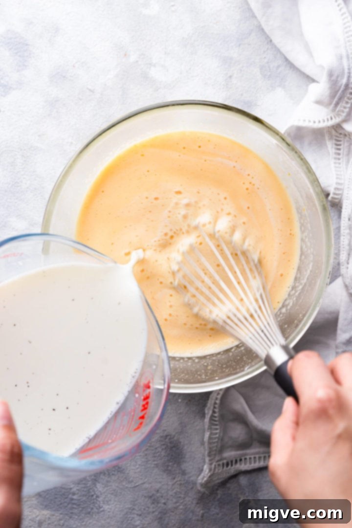 overhead shot of milk being poured into bowl with egg mixture