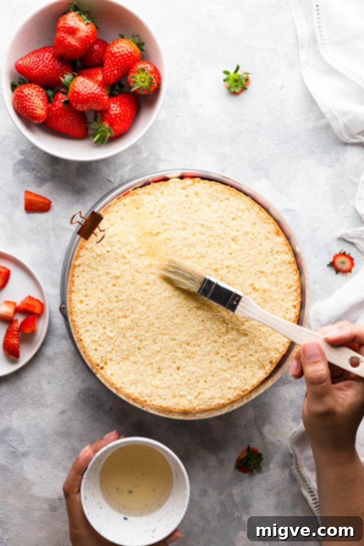 top view of a person brushing sponge cake with syrup