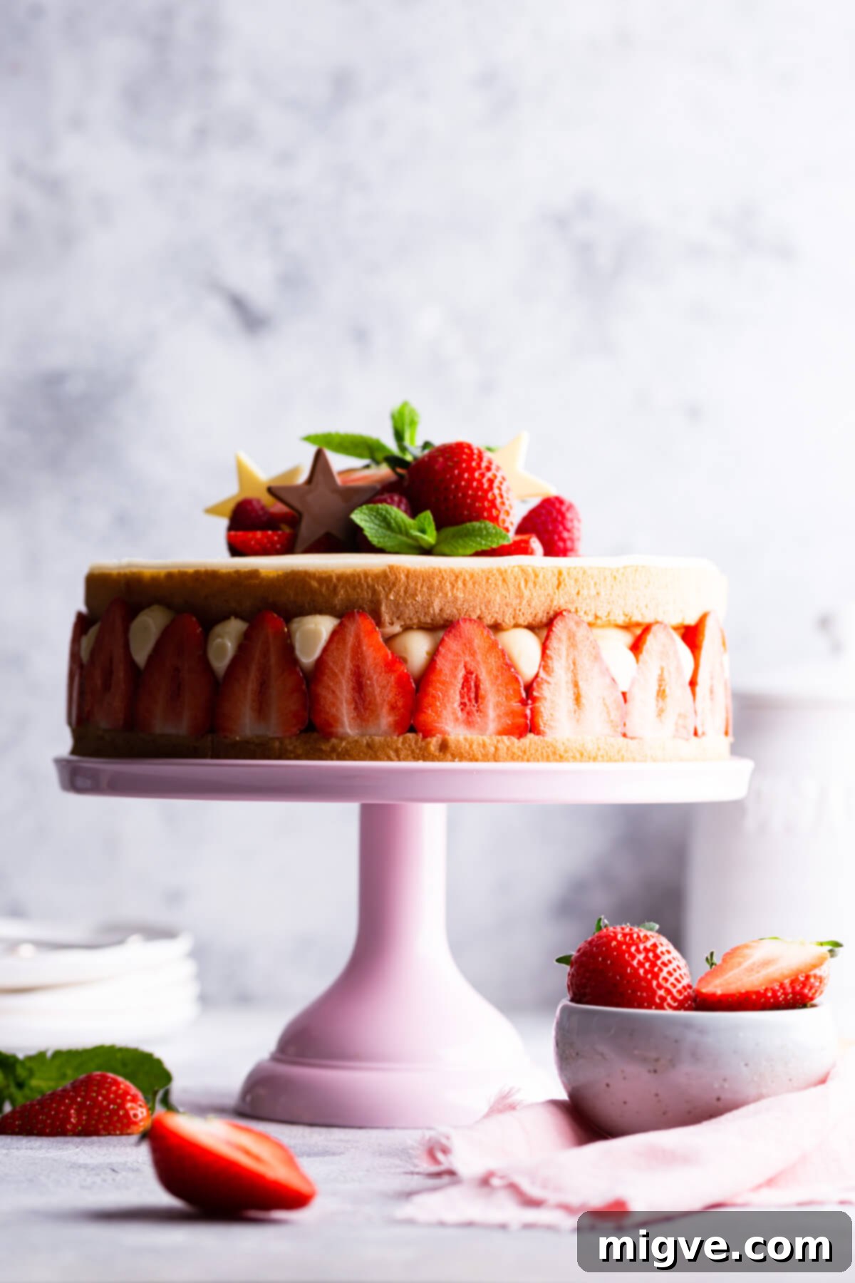 side close up of fraisier cake topped with fresh strawberries