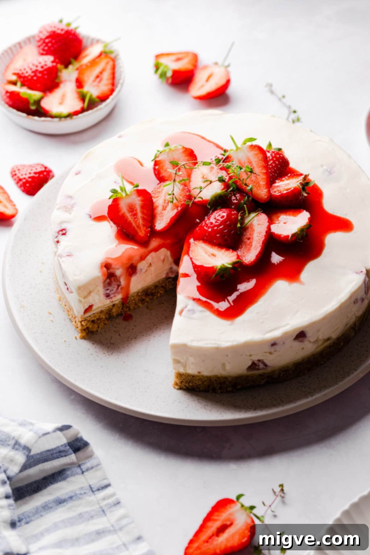 Velvet Strawberry White Chocolate Cheesecake 14 45 degree angle view of a strawberry cheesecake topped with strawberry sauce