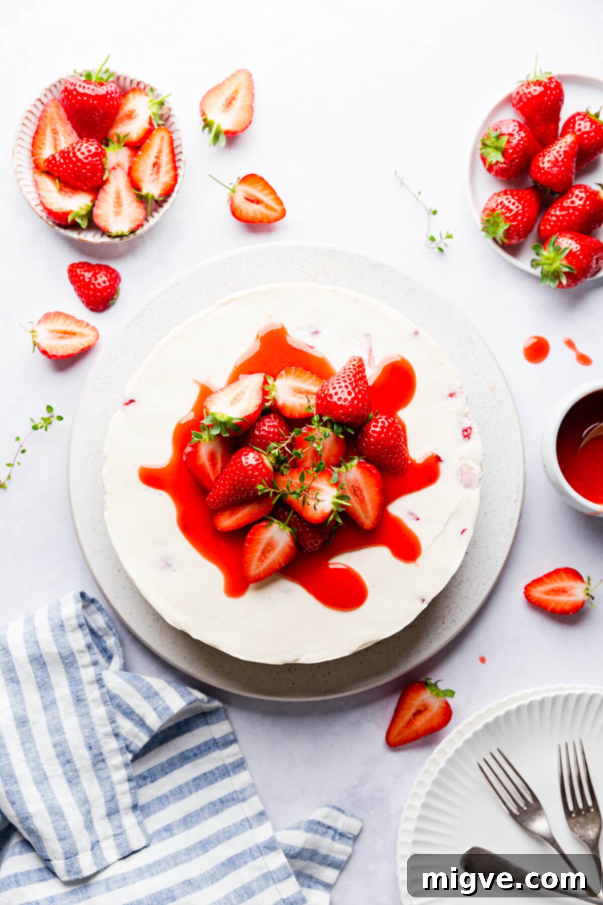 Velvet Strawberry White Chocolate Cheesecake 4 top view of a strawberry white chocolate cheesecake topped with sauce and fresh strawberries