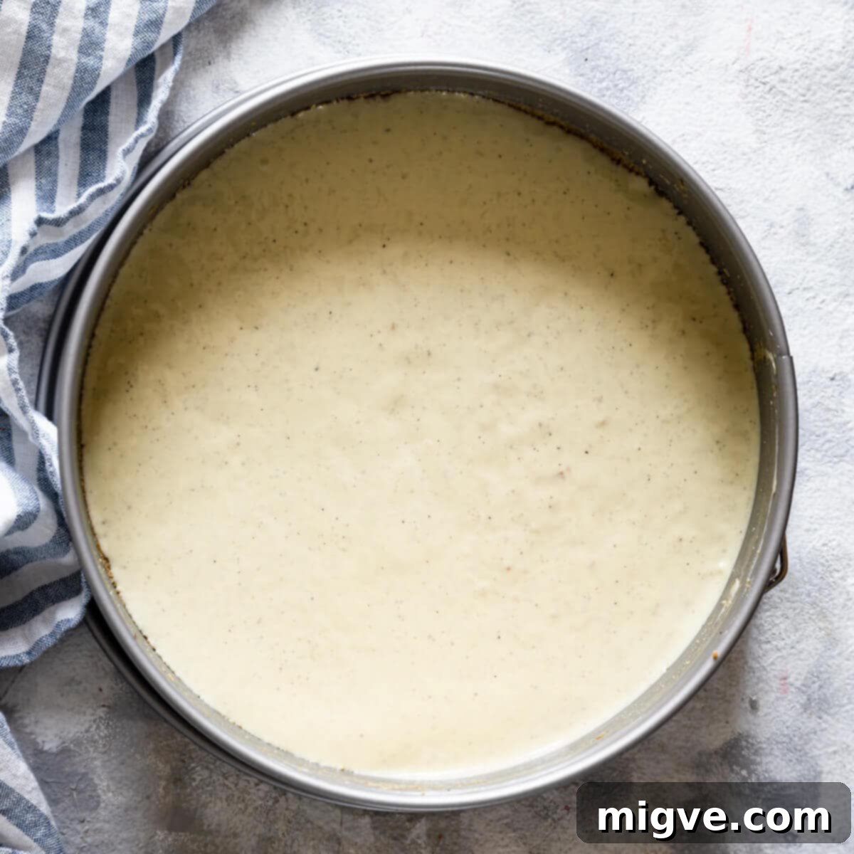 Velvet Strawberry White Chocolate Cheesecake 8 top view of a cake tin with cheesecake base topped with white chocolate