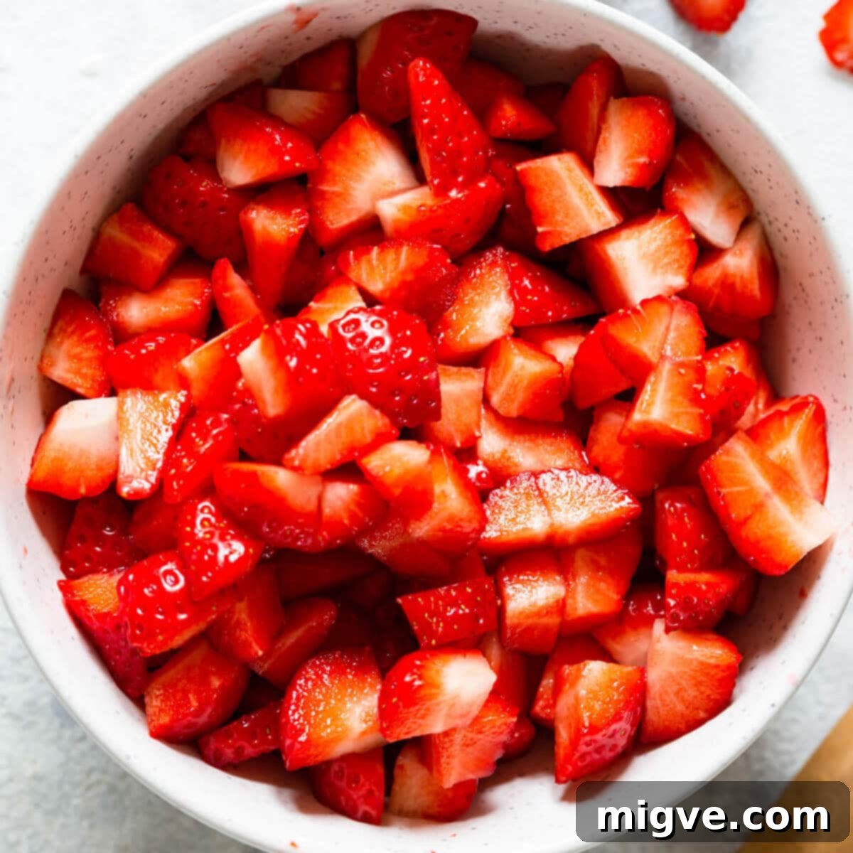 Velvet Strawberry White Chocolate Cheesecake 9 overhead shot of a bowl with chopped fresh strawberries