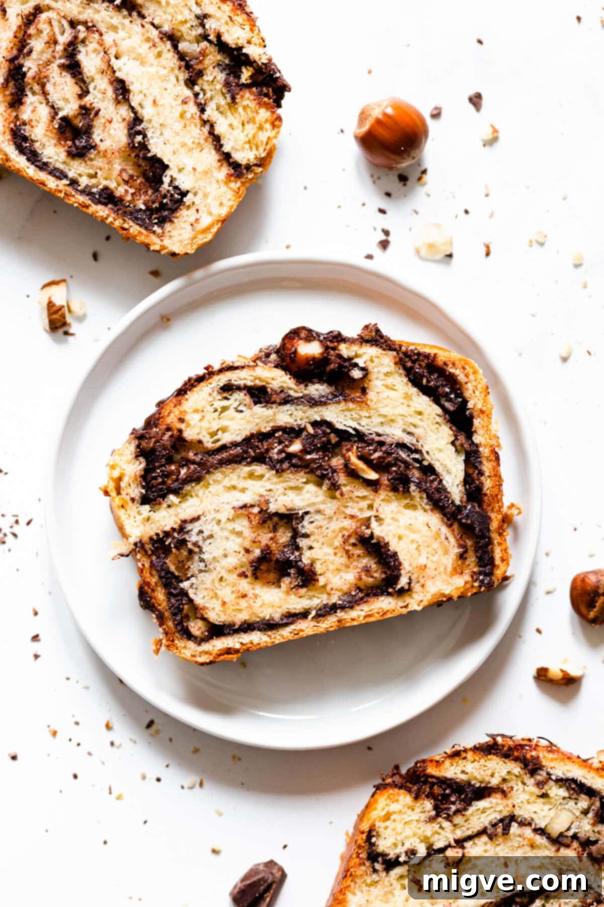 A top-down, close-up view of a sliced Nutella babka, revealing the beautiful swirls of chocolate and chopped hazelnuts within each piece.
