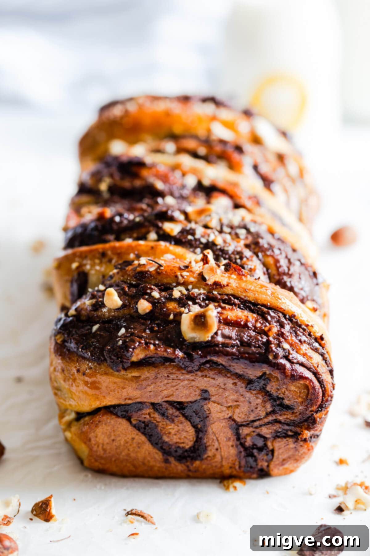 A stunning 45-degree angle view of a freshly baked chocolate hazelnut babka, highlighting its intricate braid and glossy finish.