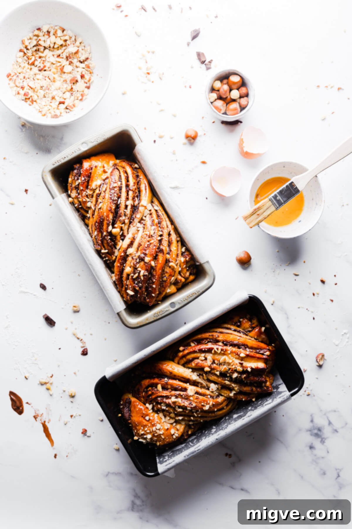 An overhead shot of two perfectly baked Nutella babkas resting in their loaf pans, ready to be glazed.
