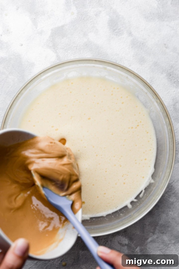 top view of peanut butter being added into the bowl with egg mixture