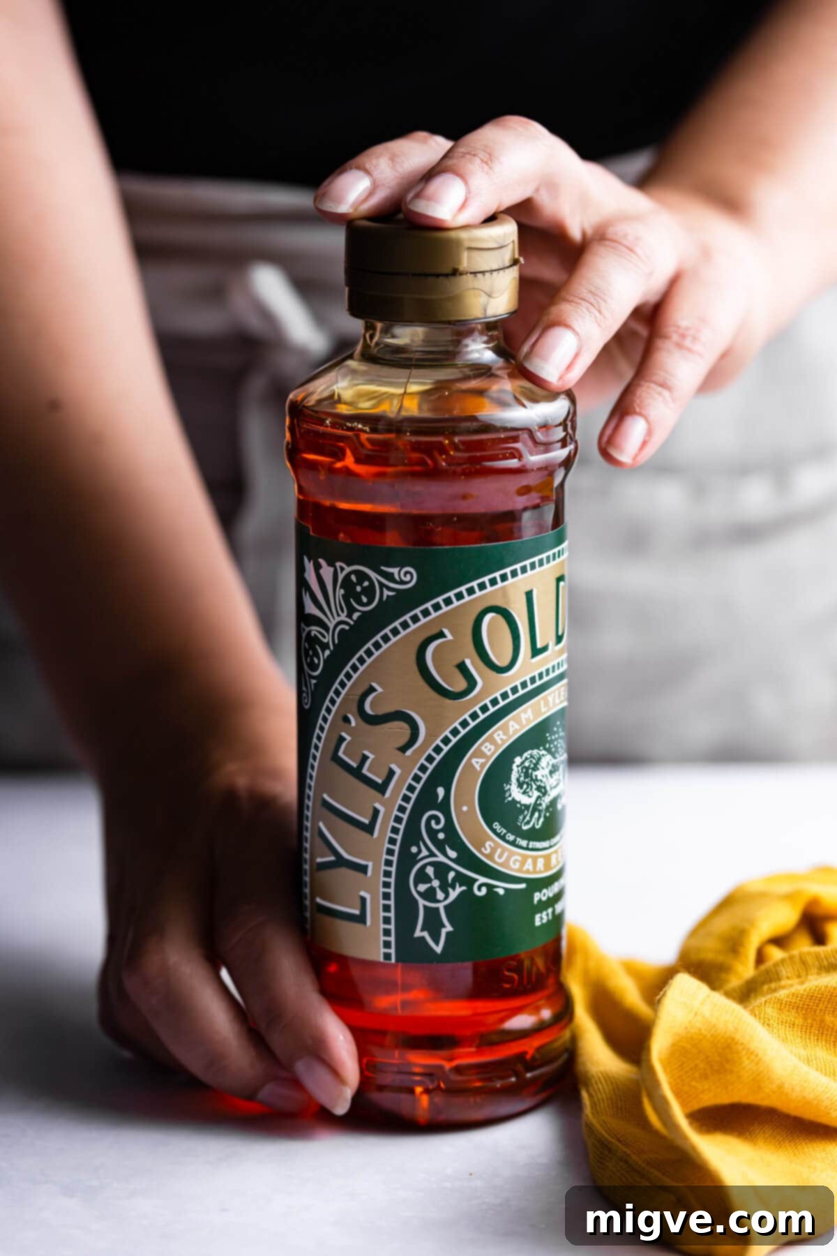 side close up at a person holding a bottle of Lyle's Golden Syrup