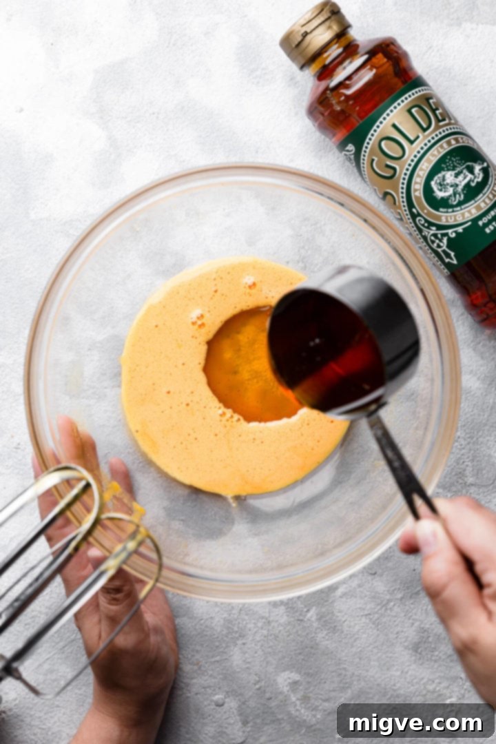 top view of golden syrup being poured into the bowl with egg yolks
