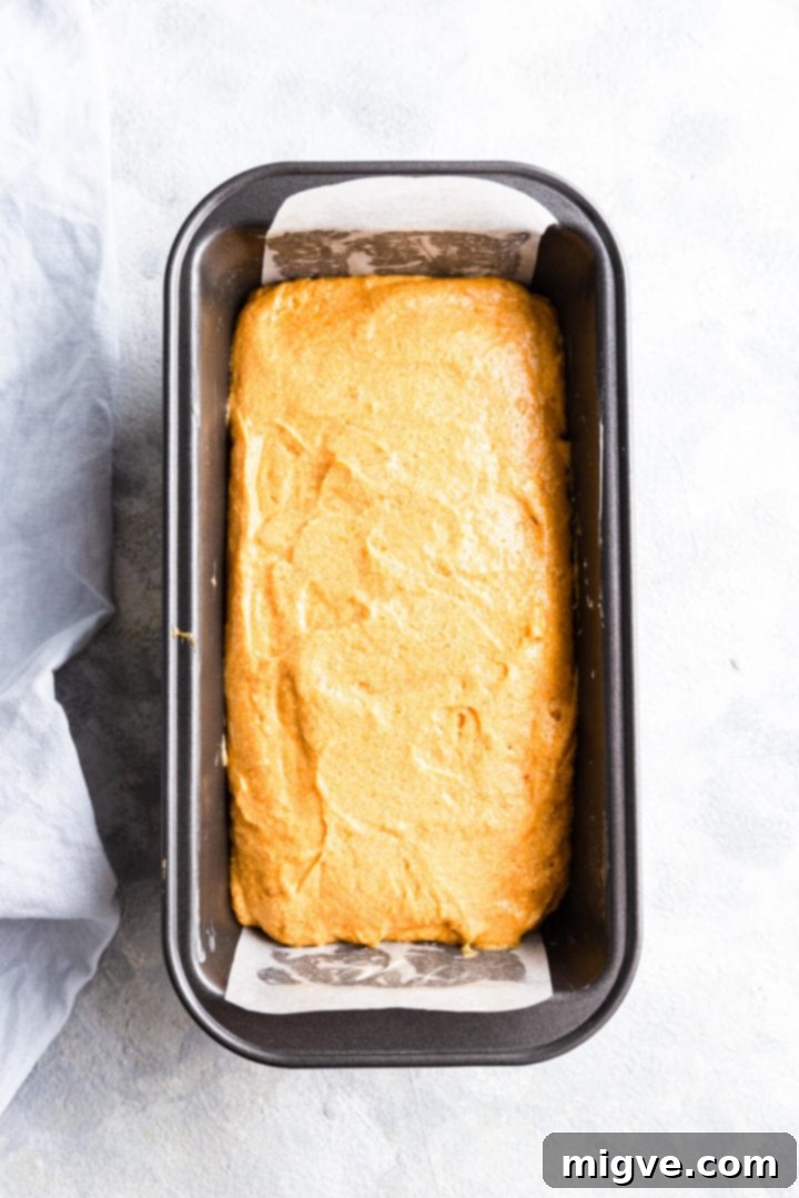 Overhead view of a baking loaf tin filled with pumpkin cake batter, ready for the oven.