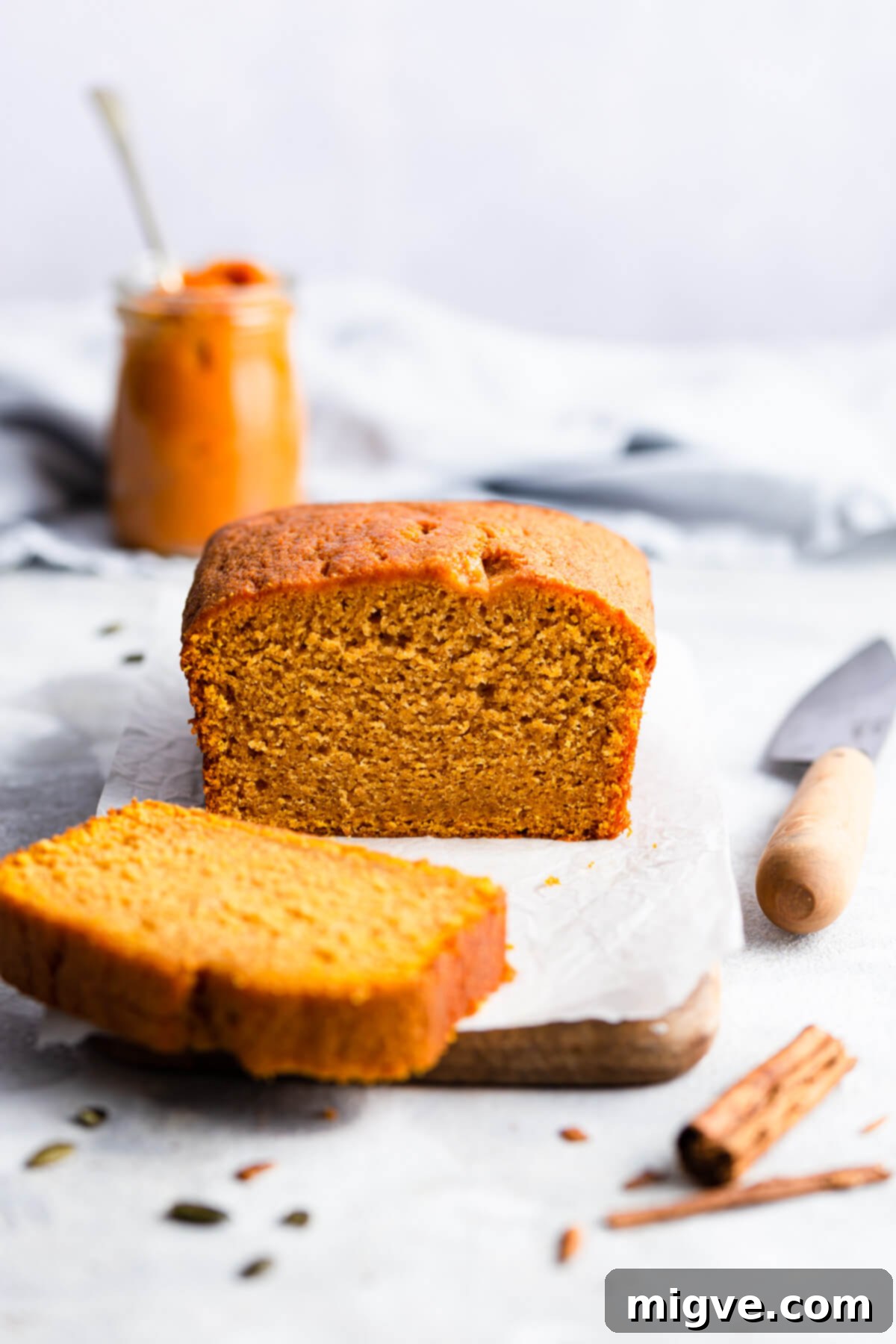 Side angle photo of a moist pumpkin loaf cake with a perfect slice cut off, showcasing its spiced interior.