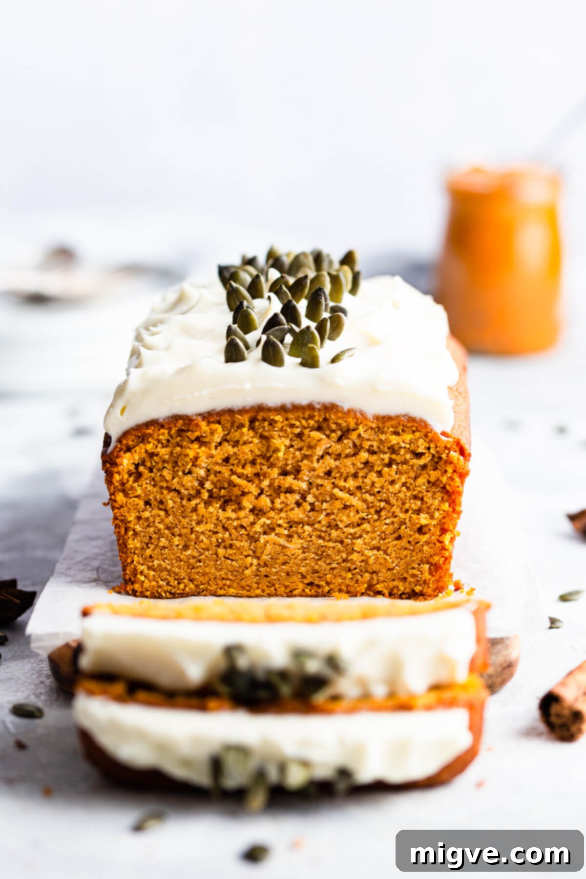 Super close-up, straight-ahead shot of a pumpkin bread loaf, with a couple of slices being cut off, revealing its moist interior.