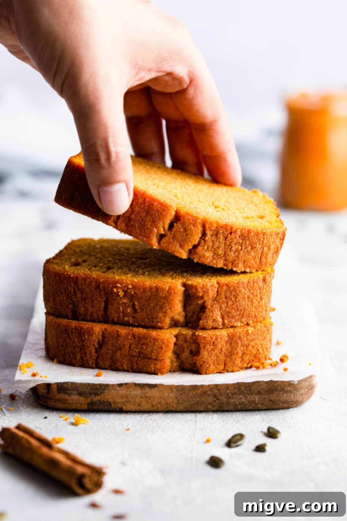 Close-up, straight-ahead shot of three slices of moist pumpkin cake, with one slice gently lifted, showcasing its tender crumb and rich color.