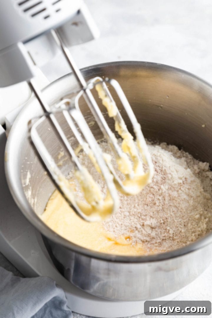 A 45-degree angle view of dry ingredients being added to the bowl with the creamed wet ingredients.