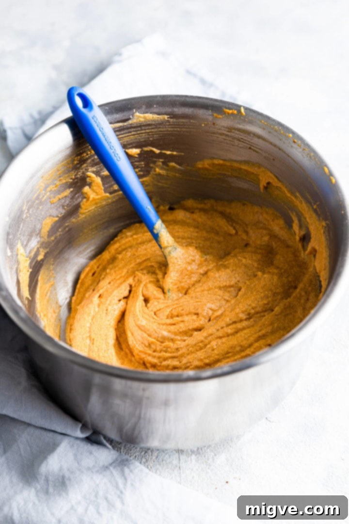 Side angle view of a mixing bowl with fully combined cake batter for pumpkin loaf cake.