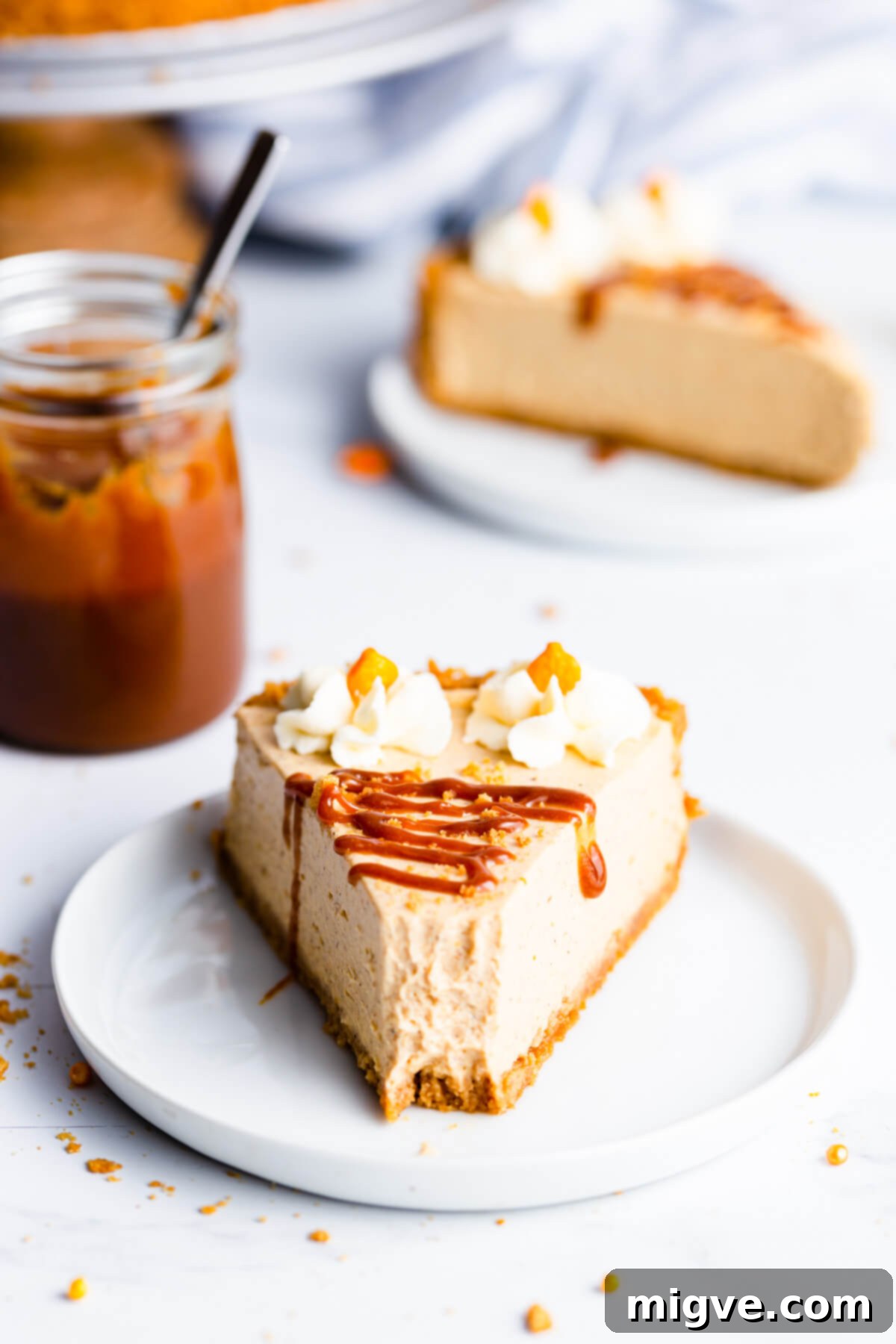 straight ahead super close up at a single slice of pumpkin cheesecake drizzled with caramel sauce