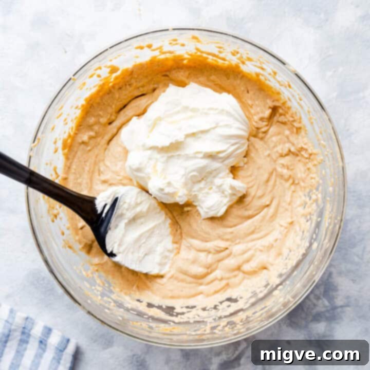 overhead shot of a bowl with the whipped cream being added to the cheesecake filling