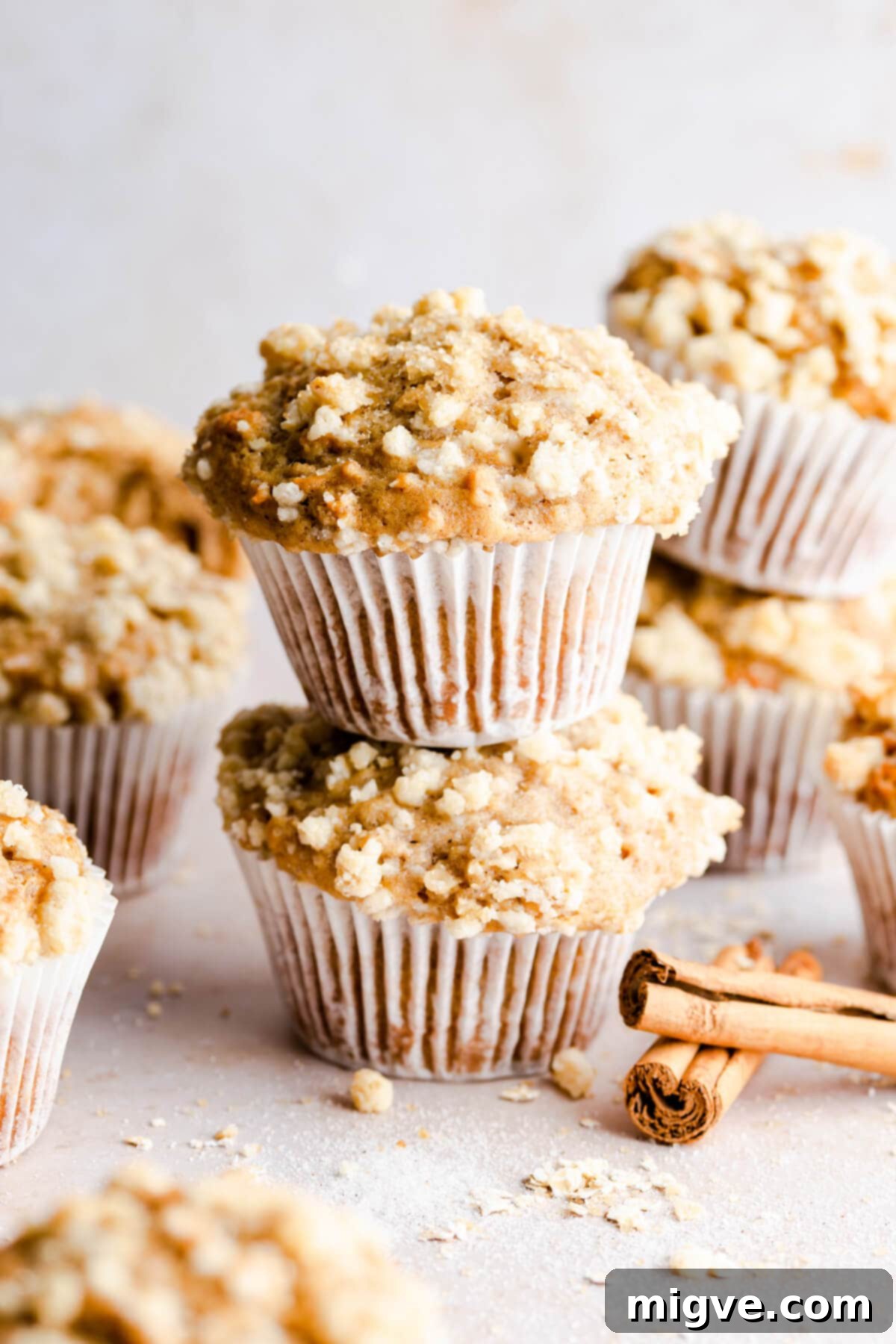 Super close-up side view of a stack of two fluffy cinnamon oatmeal muffins with crunchy topping
