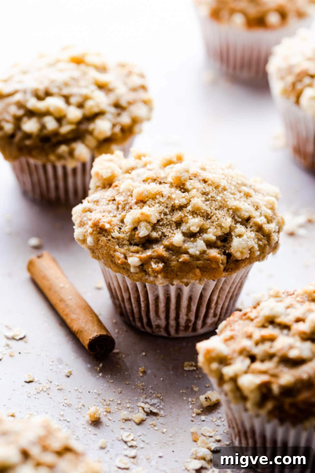 45-degree angle close-up of a single cinnamon oatmeal muffin with a cinnamon stick next to it.