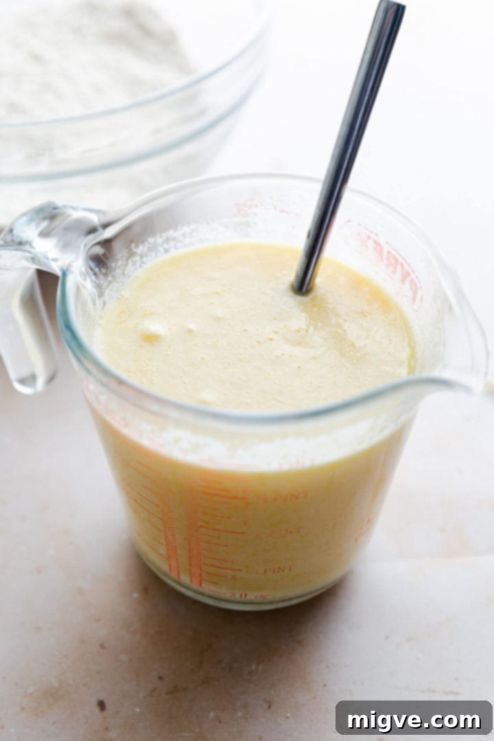 Side angle close-up of a jug containing the whisked buttermilk, egg, and melted butter mixture.