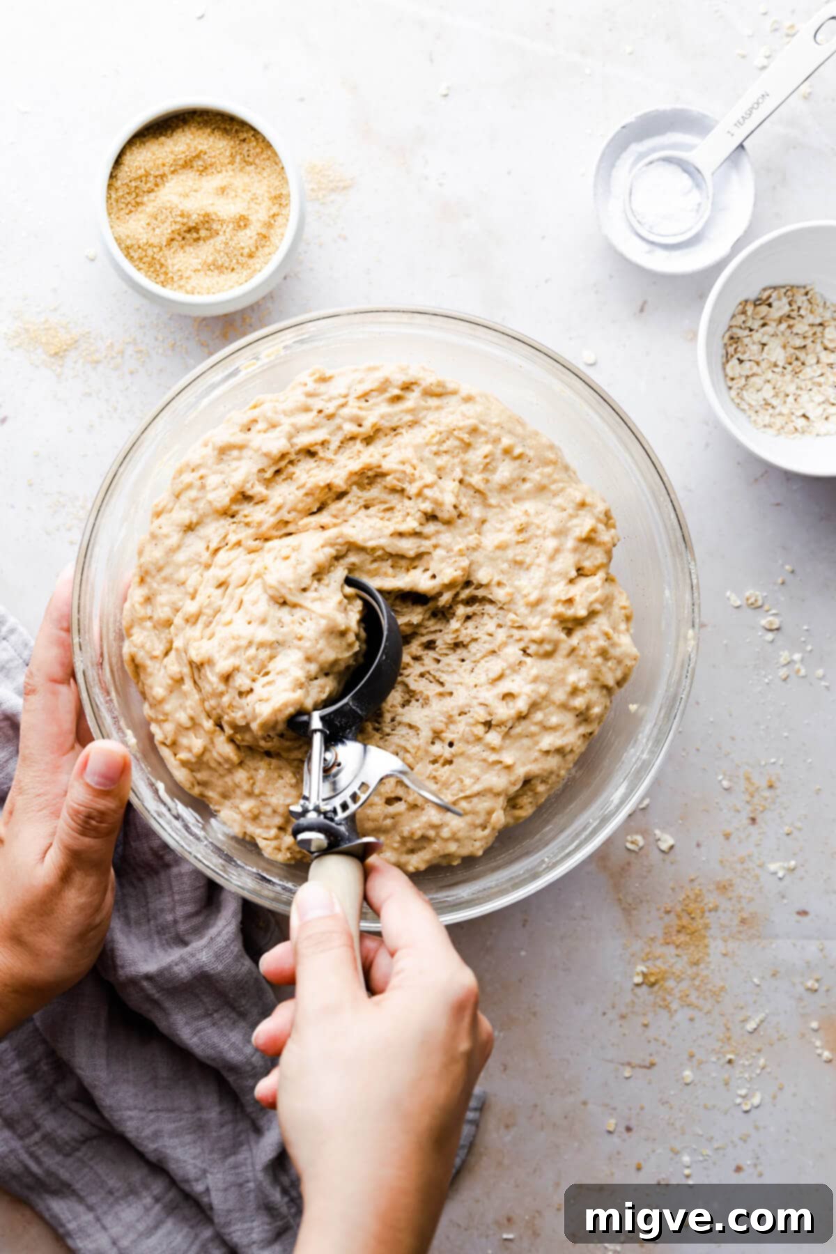 Overhead shot of a person scooping muffin batter from a large bowl into paper liners
