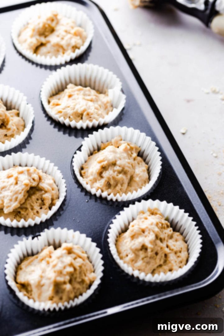45-degree angle shot of muffin batter in paper cases within a muffin tin, ready for topping.