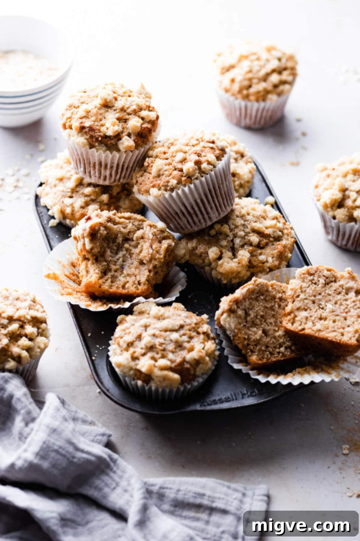 45-degree angle shot of freshly baked cinnamon oatmeal muffins piled high in a muffin tin.
