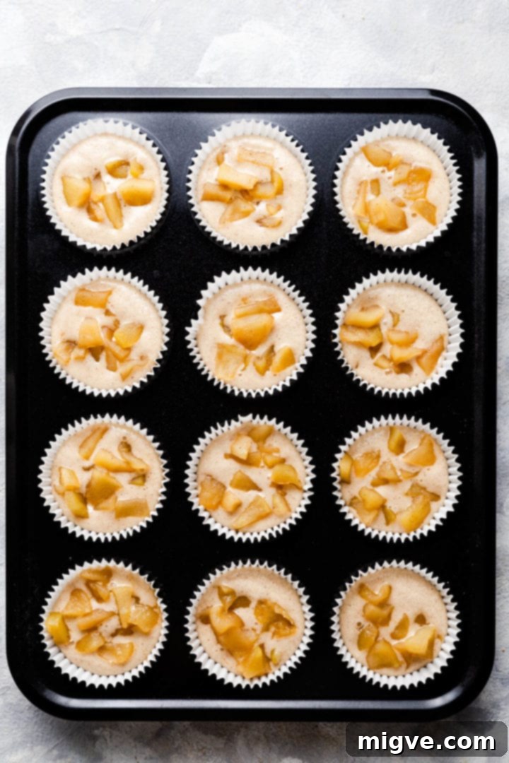 Spiced Apple Crumble Cupcakes 12 top view of muffin tin filled with cupcakes batter and topped with stewed apples