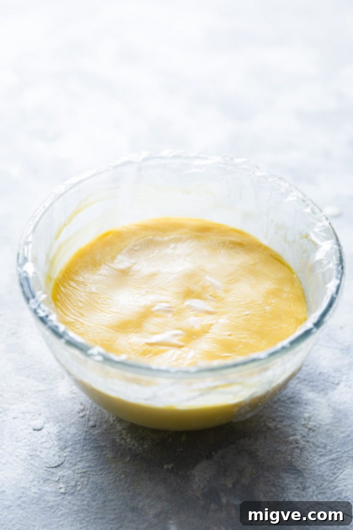 Spiced Apple Crumble Cupcakes 18 45 degree angle view of a small bowl filled with custard cream icing covered with cling film