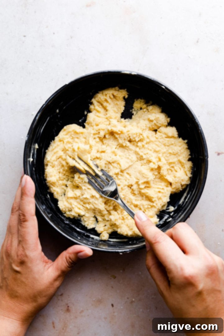 No-Fuss Apple Cake 6 overhead view of a person spreading cake batter in the tin with the fork, demonstrating the technique