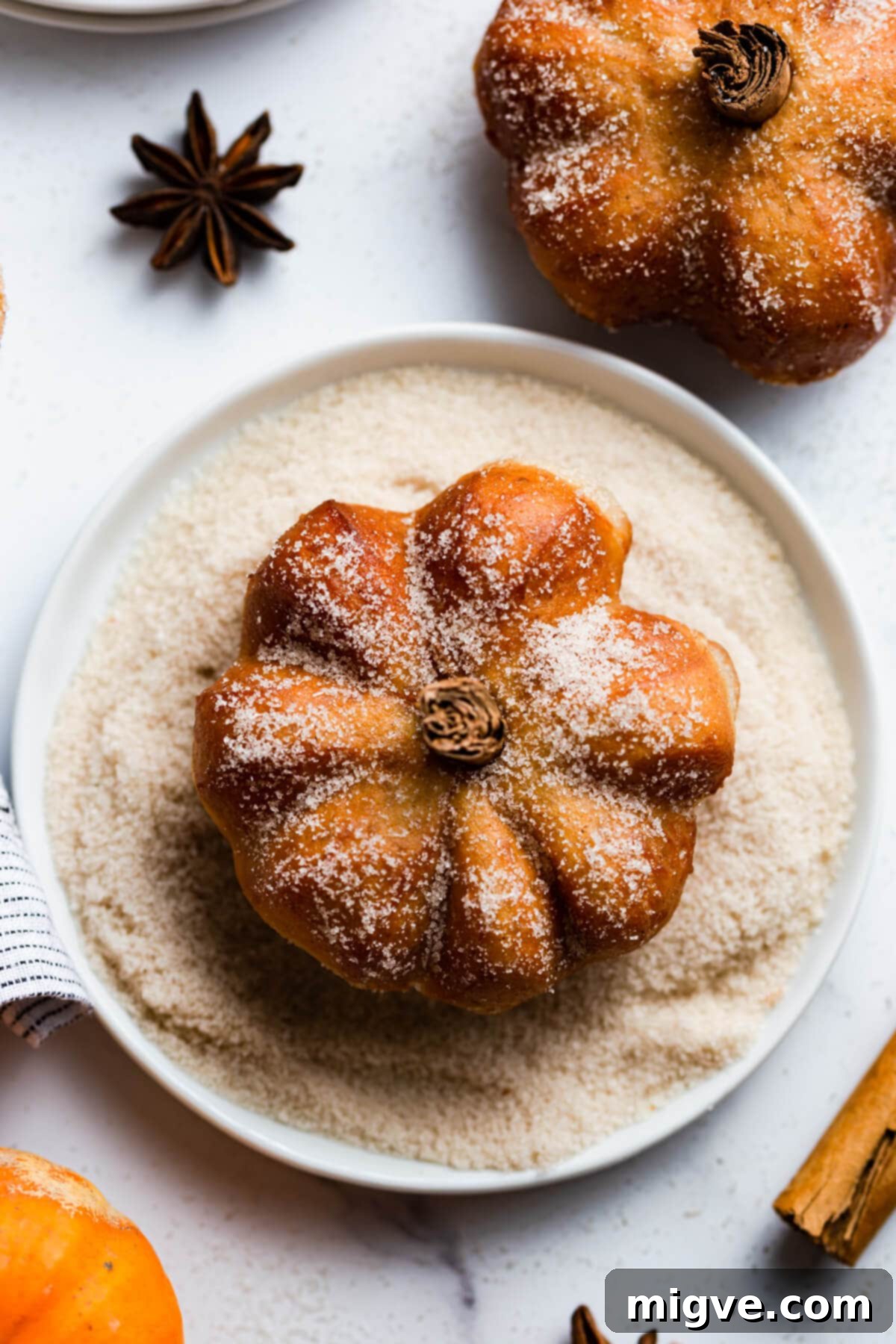 Spiced Pumpkin Doughnut Delights 15 top view of a doughnut sat in a small plate full of sugar