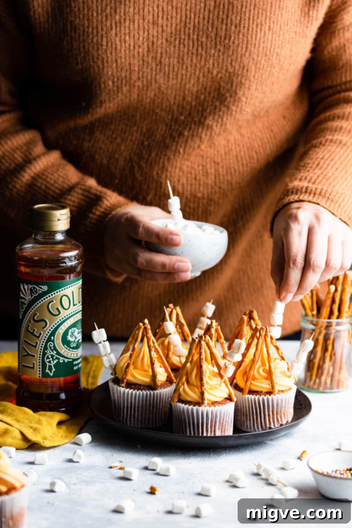 Flame-Kissed Cupcakes 7 side angle photo of a person adding mini marshmallows to cupcakes