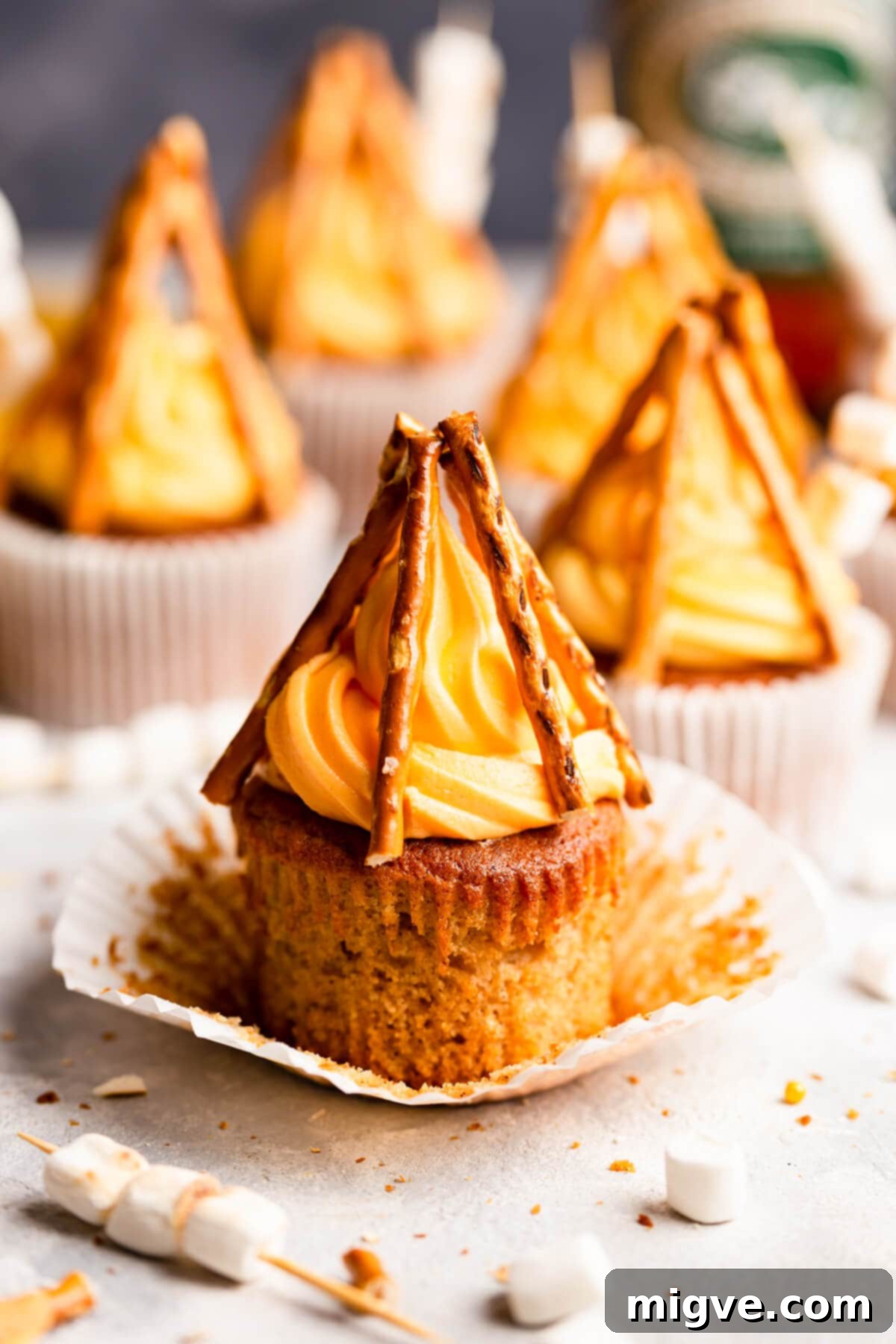 Flame-Kissed Cupcakes 9 side close up at a cupcake topped with orange buttercream and pretzel sticks