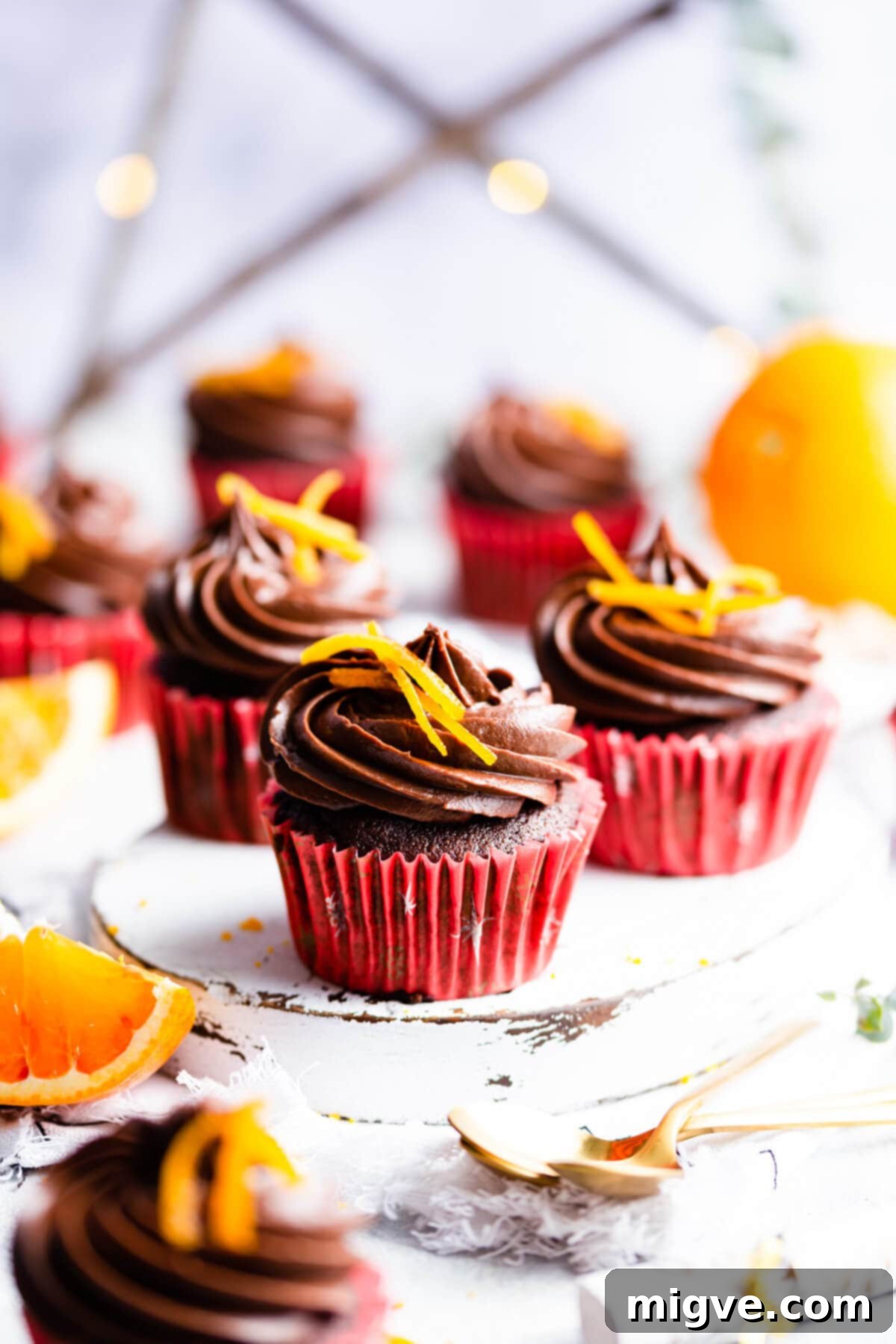 straight ahead side view of chocolate orange cupcake on small white board
